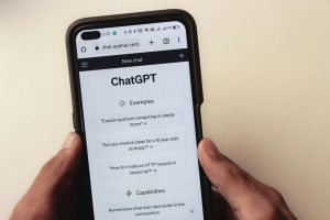 Webpage of ChatGPT, a prototype AI chatbot, is seen on the website of OpenAI, on a smartphone. Examples, capabilities, and limitations are shown.